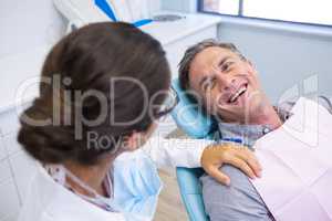 Patient sitting on chair while looking at dentist in medical clinic
