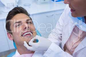 Dentist holding medical equipment while examining patient at medical clinic