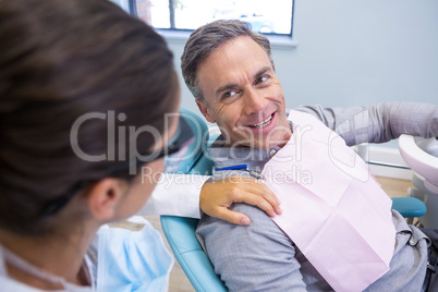 Patient looking at dentist while sitting on chair in clinic
