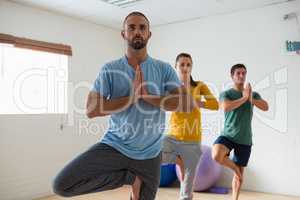 Instructor with students practicing tree pose in health club