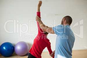 Rear view of instructor assisting student in exercising at health club