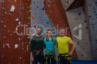 Portrait of athletes standing by climbing wall in health club
