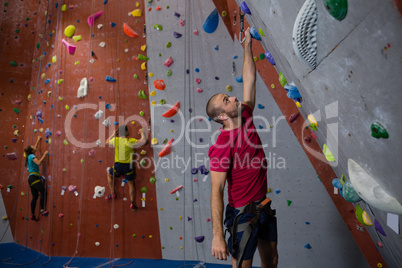 Dedicated athletes and trainer climbing wall in club