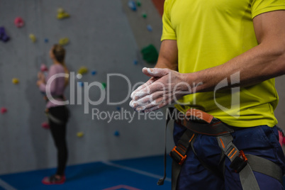 Midsection of male athlete applying chalk powder to hands in club