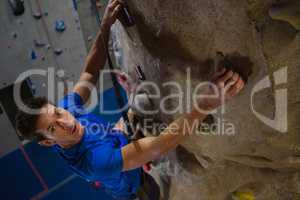Portrait of male athlete climbing wall in fitness studio