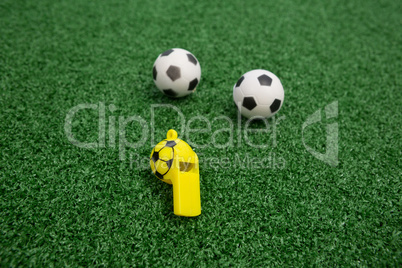 Whistle and footballs on artificial grass