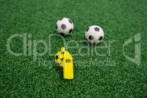 Whistle and footballs on artificial grass