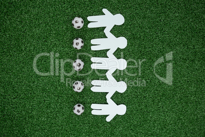 Paper cut outs and footballs arranged on artificial grass