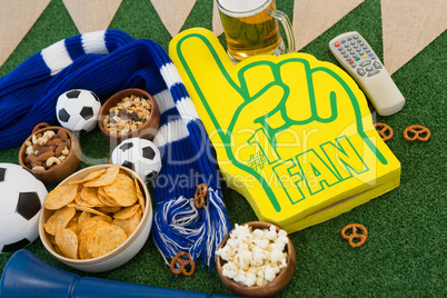 Foam hand, snacks and footballs on artificial grass
