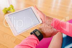 Woman holding digital tablet while using smartwatch