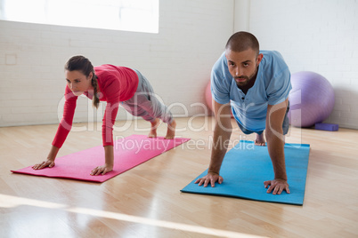 Yoga instructor with student exercising in club