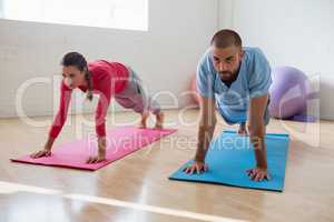Yoga instructor with student exercising in club
