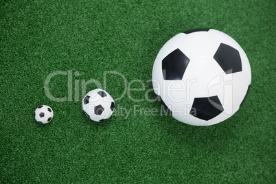 Various size of footballs on artificial grass