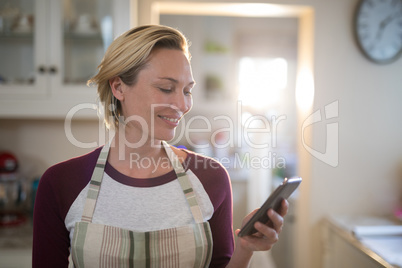 Woman using mobile phone in the kitchen