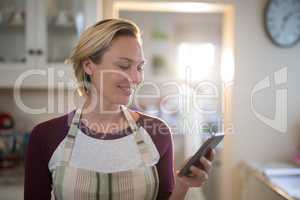 Woman using mobile phone in the kitchen