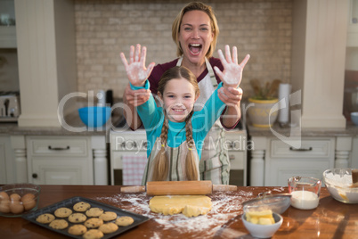 Mother and daughter having fun while preparing cookies in kitchen