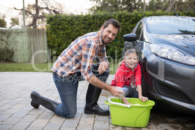 Teenage girl and father washing a car on a sunny day