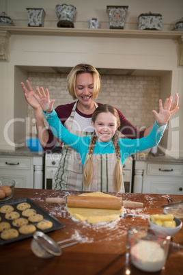 Mother and daughter having fun while preparing cookies in kitchen