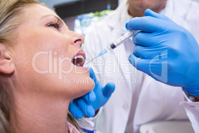 Close up of dentist holding syringe by patient