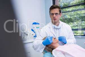 Portrait of dentist cleaning woman teeth while standing against wall