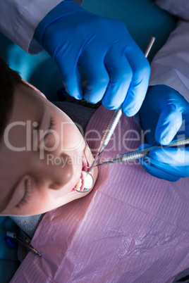 Dentist holding medical equipment while examining boy at clinic