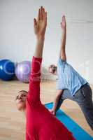 Male Instructor with student practicing triange pose in health club