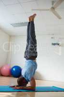 Yoga instructor doing forearm stand at health club