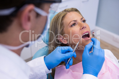 Dentist examining woman mouth at clinic