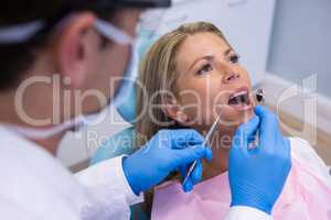 Dentist examining woman mouth at clinic