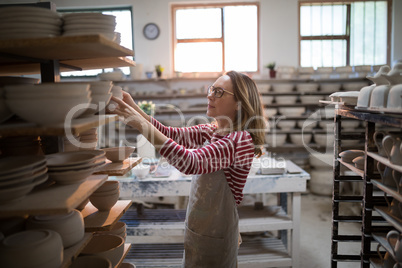 Female potter placing bowl in shelf