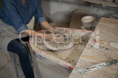 Mid section of female potter molding clay