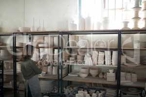 Female potter using digital tablet near shelf