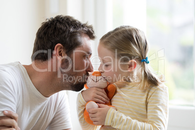Father and daughter kissing soft toy