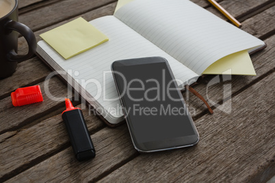 Organizer, coffee, mobile phone and stationery on wooden plank