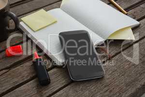 Organizer, coffee, mobile phone and stationery on wooden plank