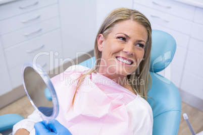 Smiling woman looking away while holding mirror
