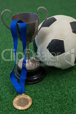 Football, trophy and medal on artificial grass