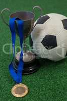 Football, trophy and medal on artificial grass