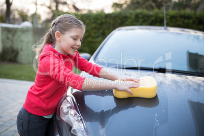 Teenage girl washing a car on a sunny day