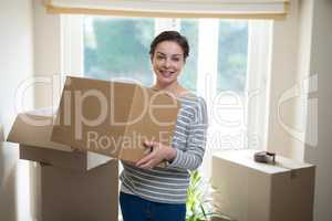 Woman carrying cardboard boxes in living room