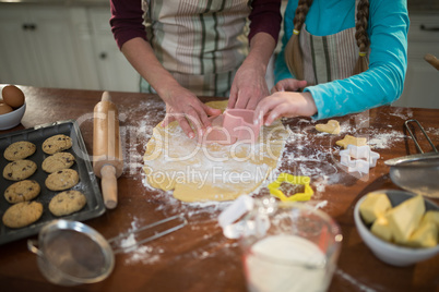 Mother and daughter preparing cookies in kitchen