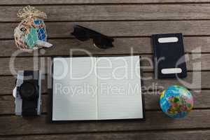 Open diary surrounded with travelling accessories