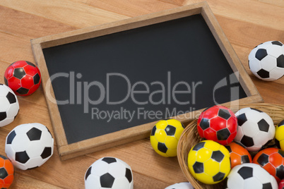 Colorful footballs and slate on wooden table