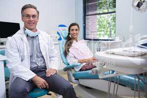 Portrait of smiling dentist and patient standing on chair