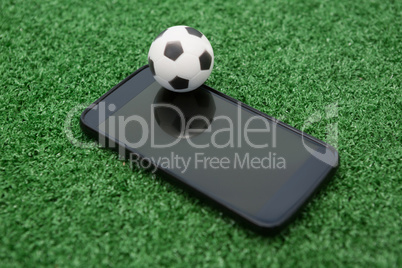 Football and mobile phone on artificial grass