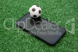 Football and mobile phone on artificial grass