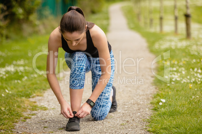 Woman tying shoes laces in the park