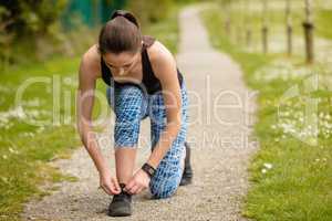 Woman tying shoes laces in the park