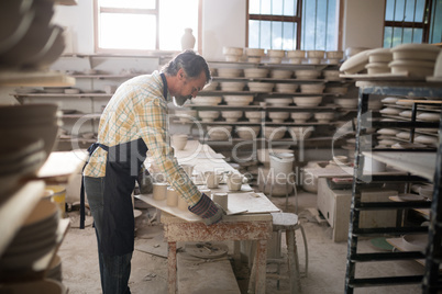 Male potter working at worktop