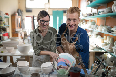 Male and female potter holding bowl